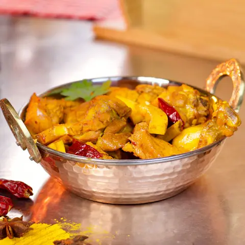 Spicy chicken curry with dried red chilies in a metal bowl