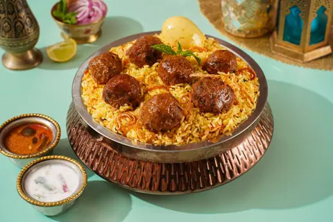 Plate of biryani topped with meatballs and boiled egg