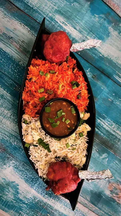 Plate of biryani rice with dal and two pieces of chicken lollipop