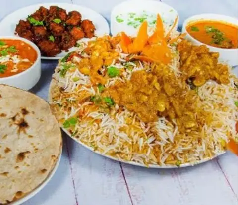 Plate of biryani with curry, roti, and side dishes