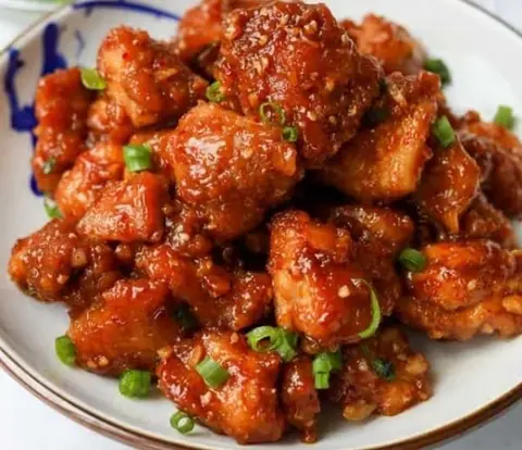 Spicy Chinese-style fried chicken pieces garnished with chopped green onions