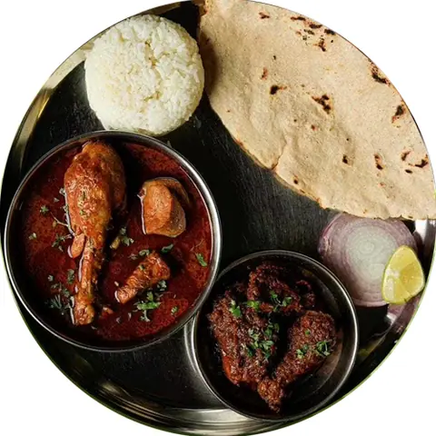 South Indian meal with chicken curry, fried chicken, white rice, papad, onion, and lemon