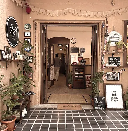 Entrance of Mauji - The Time Cafe with plants and decor in Khadki, Pune