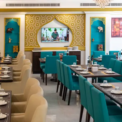 Dining area with teal and beige chairs and decorative wall in The Yellow Chilli