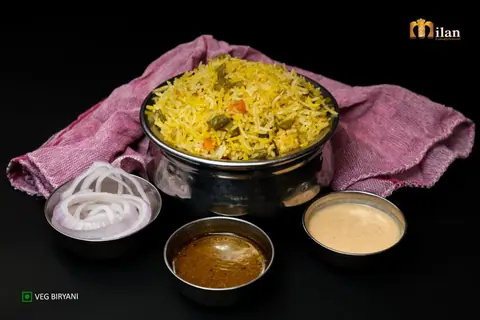 Veg biryani served with sliced onions and two types of chutney
