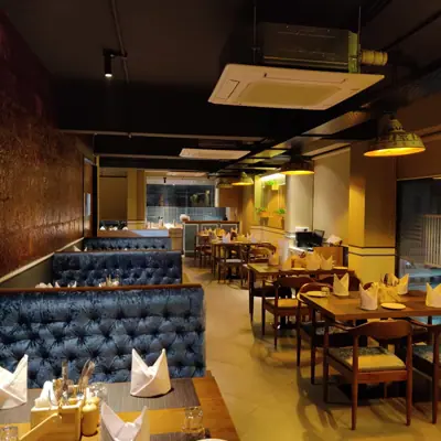 Dining area with blue cushioned seats and wooden tables set with napkins