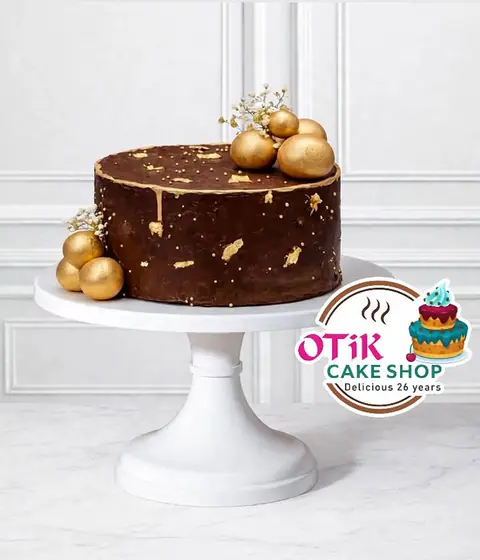 Chocolate cake with gold decoration on white cake stand