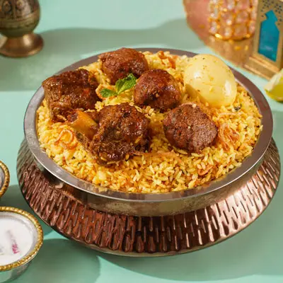 Plate of biryani with meat pieces and boiled egg on top