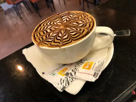 cup of coffee with intricate chocolate and cream latte art on top