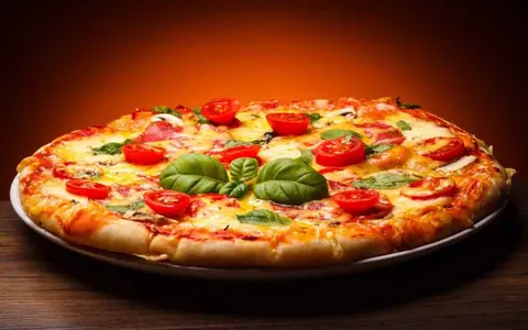 Cheese pizza topped with cherry tomatoes and basil leaves