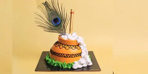 Decorative orange cake with white cream and a peacock feather