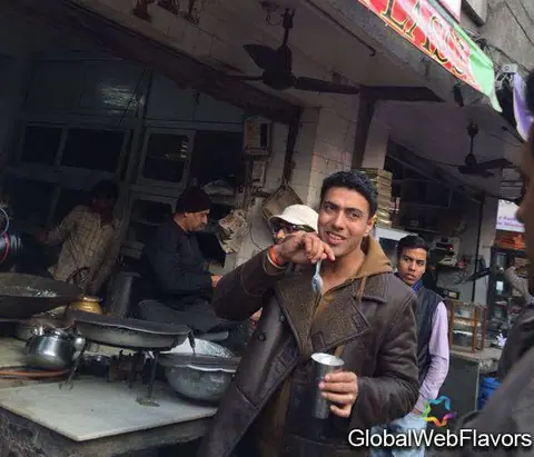 Man tasting lassi in a steel glass at an outdoor stall