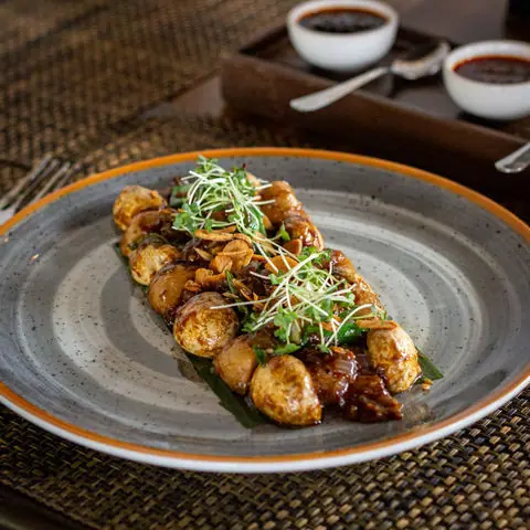 Asian-style grilled mushrooms garnished with microgreens on a plate