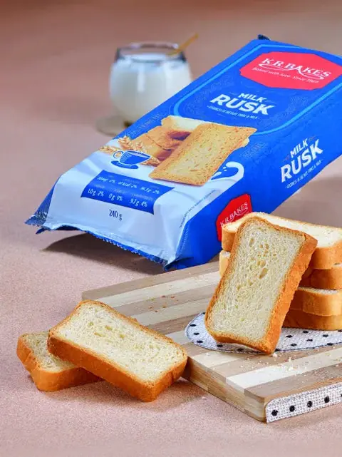 Milk rusk slices with packaging and a glass of milk in background