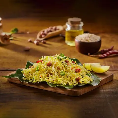 Lemon rice garnished with peanuts and herbs on a banana leaf
