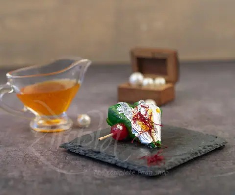 Paan wrapped in silver leaf with a small glass of syrup