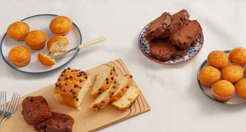Assorted bakery items including muffins, chocolate chip cake, and brownies on plates