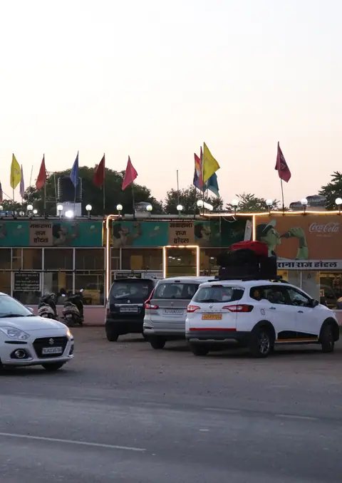 Exterior view of Makrana Raj Restaurant with parked cars and colorful flags